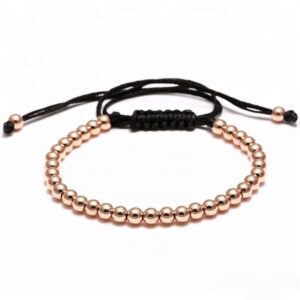 Rose gold stainless steel round beads bracelet with an adjustable black braided macrame cord closure on a white background.