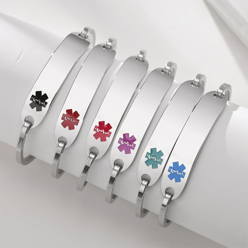 Row of silver stainless steel medical alert bracelets displaying different colored emergency symbols including black, red, purple, teal, and blue.