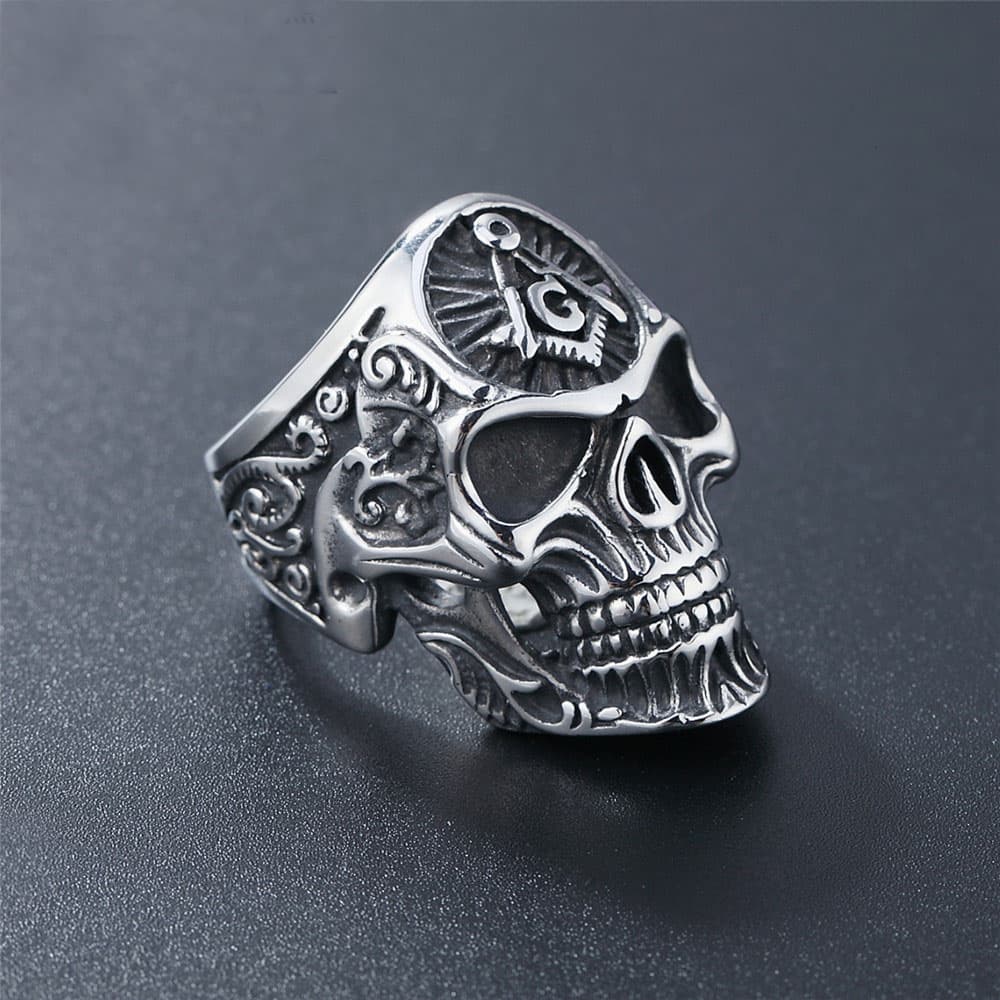 Three-quarter side angle view of a men's stainless steel Masonic skull biker ring showing intricate gothic engraved scrollwork along the band.