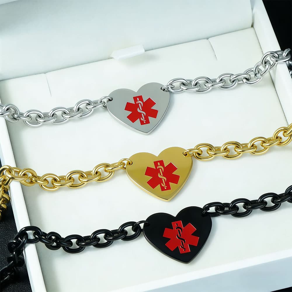 Three customized medical alert ID heart charm bracelets in silver, gold, and black stainless steel displayed in a white gift box.