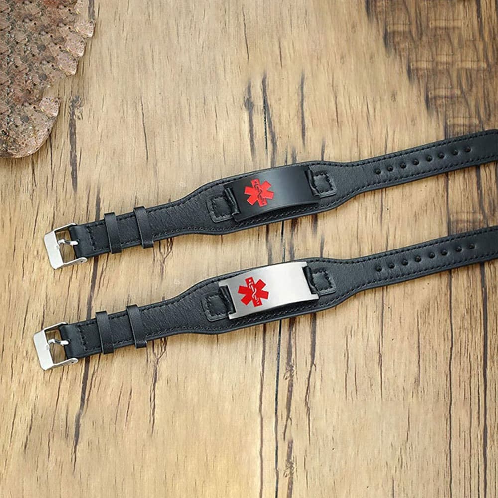 Flat lay view of two black leather medical alert bracelets with custom engravable plates in black and silver finishes featuring a red Star of Life.