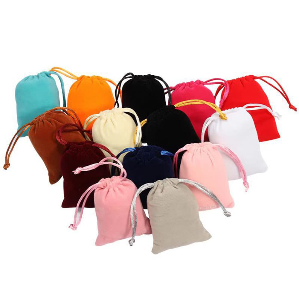 A diverse arrangement of small velvet drawstring jewelry pouches in multiple colors including pink, blue, red, white, orange, and gray.