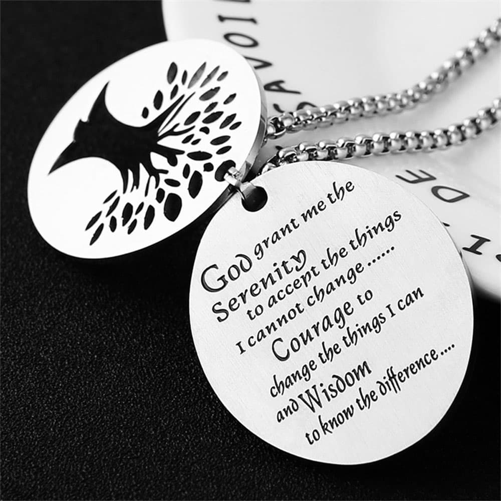 Close-up detail of stainless steel pendant showing clear laser engraved Serenity Prayer text alongside Tree of Life disc.