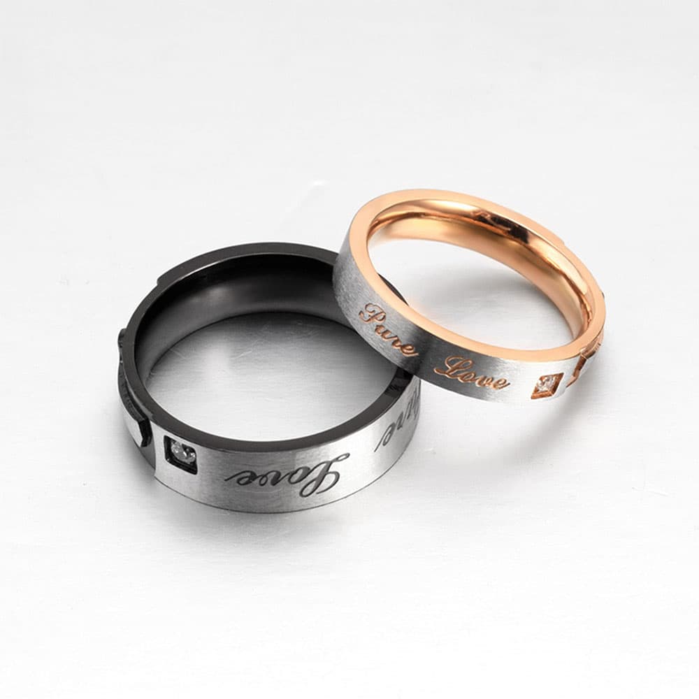 Close-up of stainless steel couple rings engraved with Pure Love script in black and rose gold two-tone stainless steel.