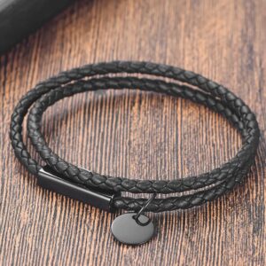 Personalized all-black braided genuine leather double-wrap bracelet with engravable stainless steel bar and round disc charm on a wooden background.